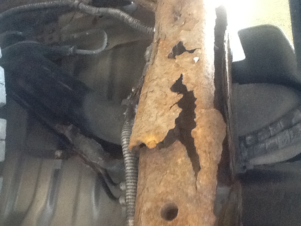 A Honda Passport chassis frame with a large irregular hole caused by advanced corrosion